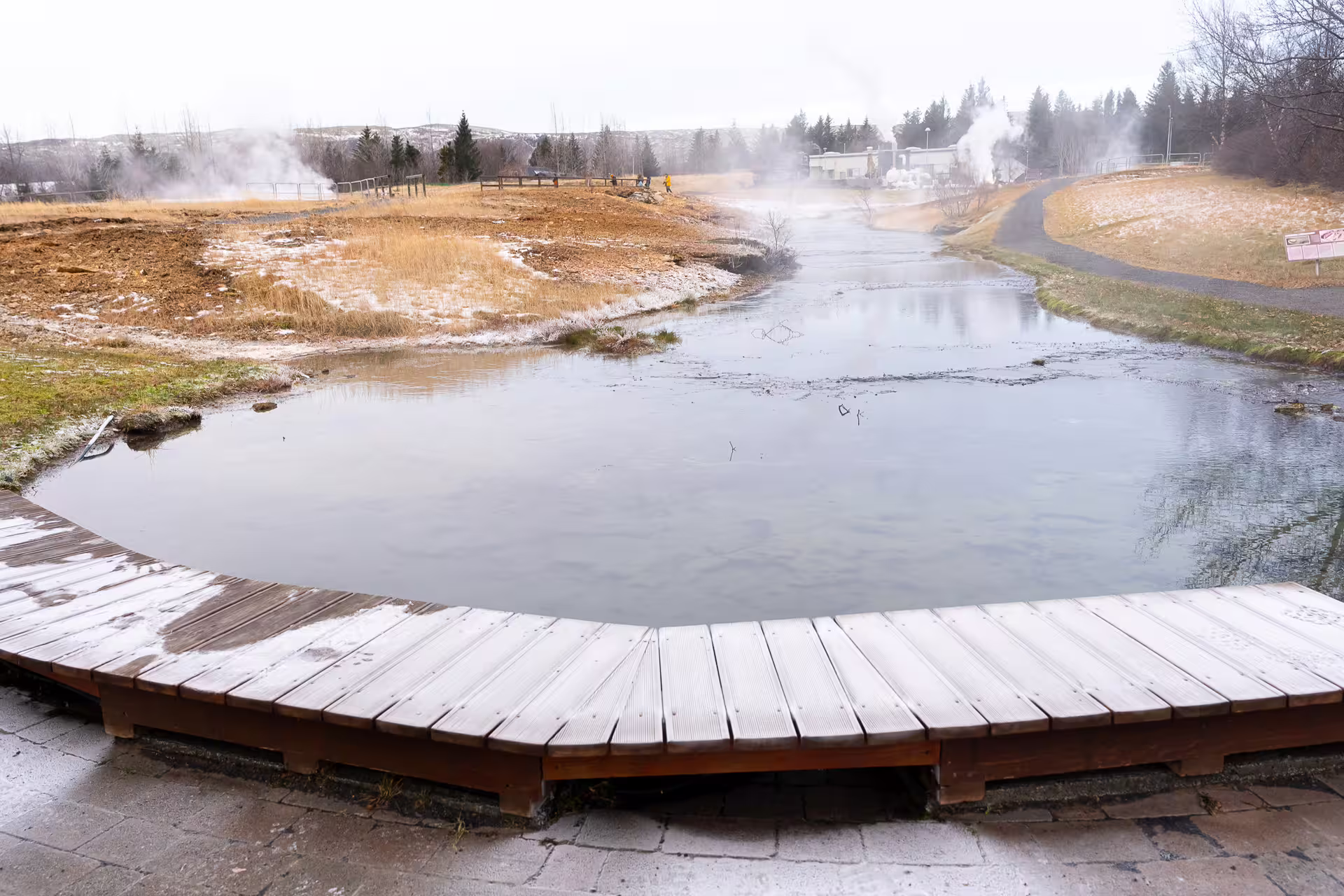 Steaming geothermal hot spring pool with wooden boardwalk at Iceland's Golden Circle in winter