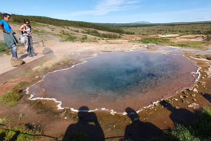 Tourists viewing a steaming geothermal hot spring pool on the Golden Circle tour in Iceland