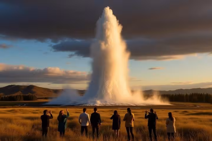 Tourists watching Old Faithful geyser eruption at golden hour on Iceland's Golden Circle tour