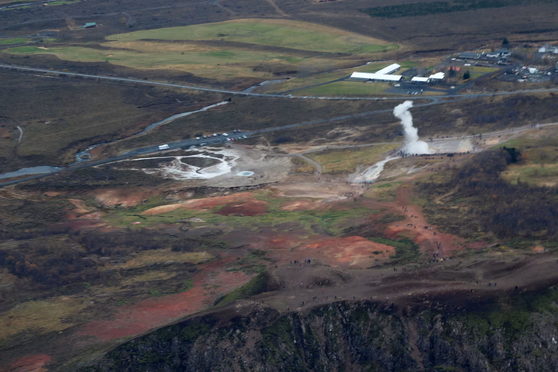 Aerial view of Geysir geothermal area with erupting geyser and tourists on Golden Circle Iceland