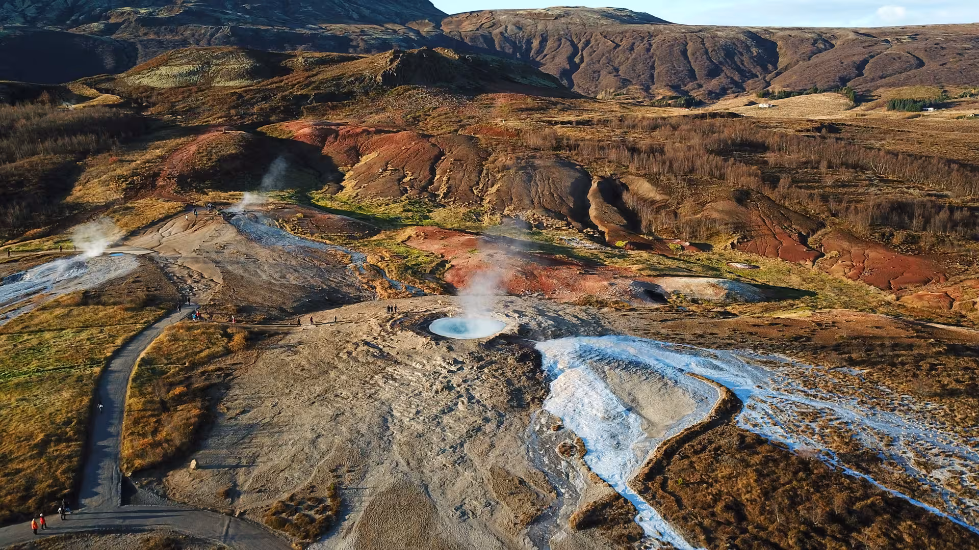 Aerial view of Geysir hot spring area with steam vents and colorful geothermal landscape in Iceland