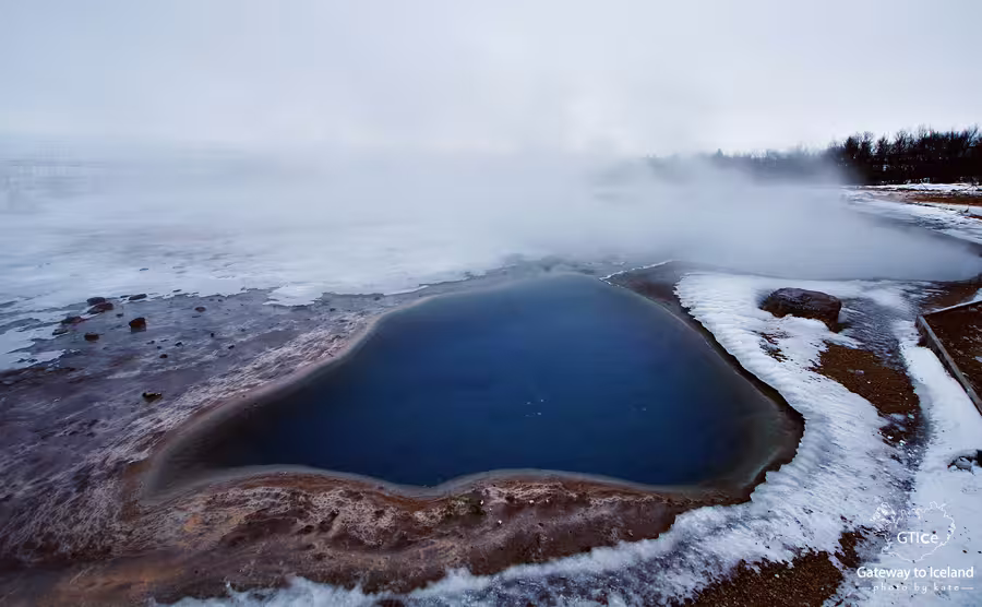 Steaming blue geothermal hot spring pool at Geysir geothermal area in winter, Iceland