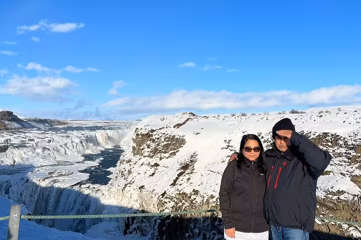 Couple posing at Gullfoss waterfall on Golden Circle tour, snow-covered canyon in winter Iceland