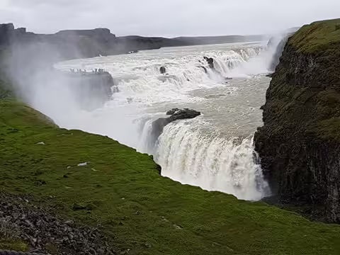Powerful Gullfoss waterfall cascading into a canyon surrounded by green cliffs in Iceland