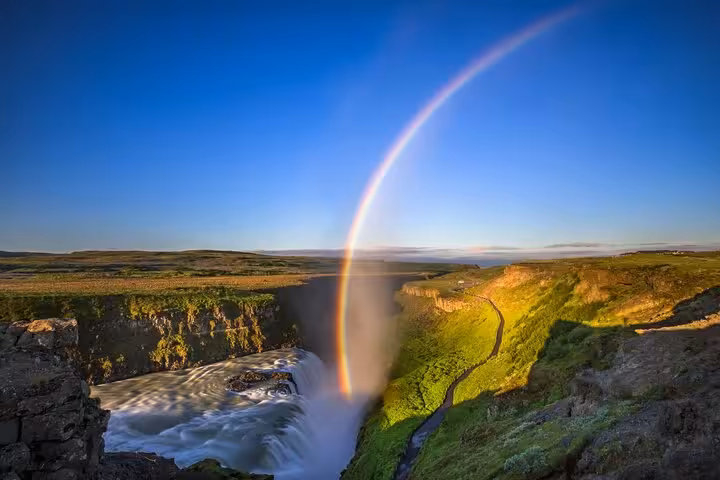 Rainbow arching over Gullfoss waterfall with green canyon landscape on Iceland's Golden Circle route