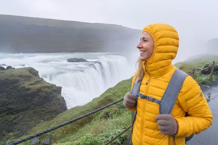 Smiling woman in yellow jacket at Gullfoss waterfall on Golden Circle tour from Reykjavik