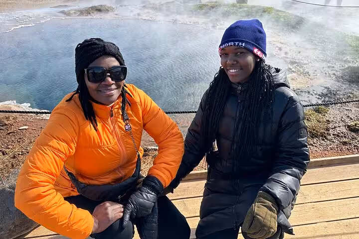 Two women in winter jackets smiling at Hvammsvík Hot Springs on Golden Circle tour