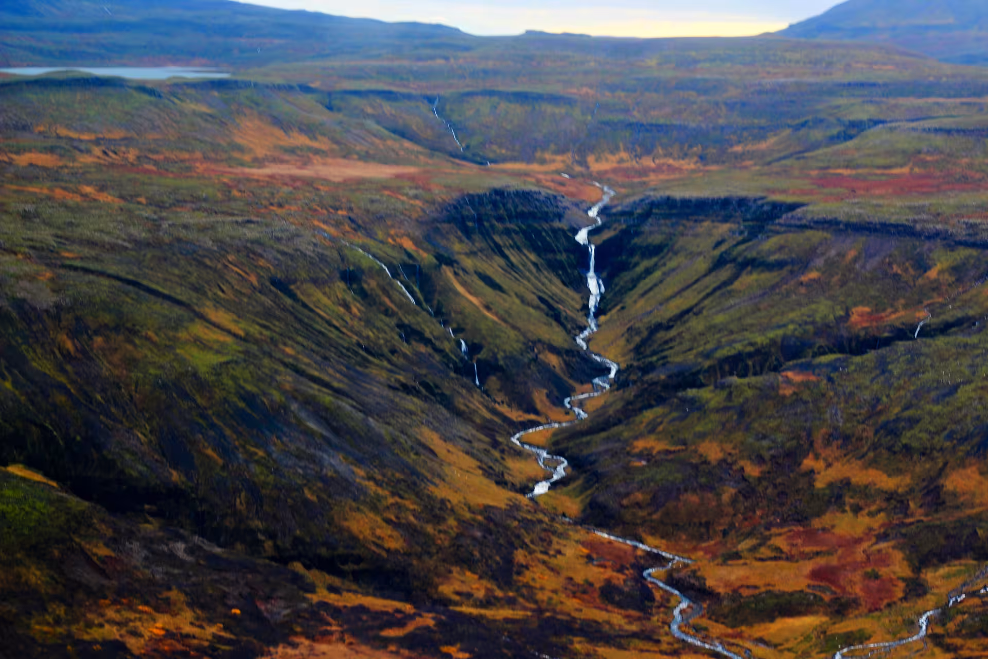 Aerial view of winding river through volcanic canyon with autumn tundra colors in Iceland