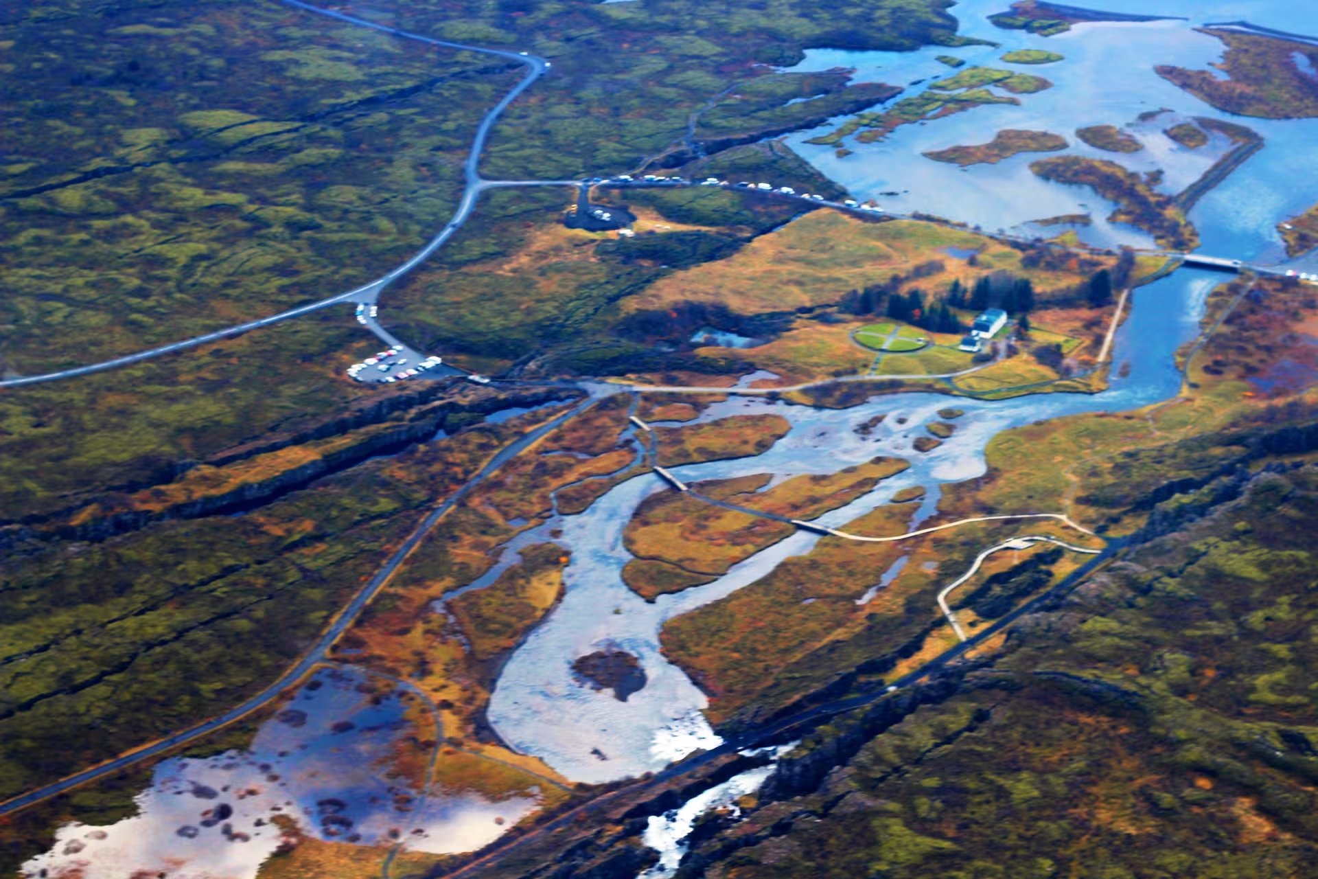 Aerial view of Icelandic wetlands, tidal rivers, and winding roads near Reykjavik from airplane tour