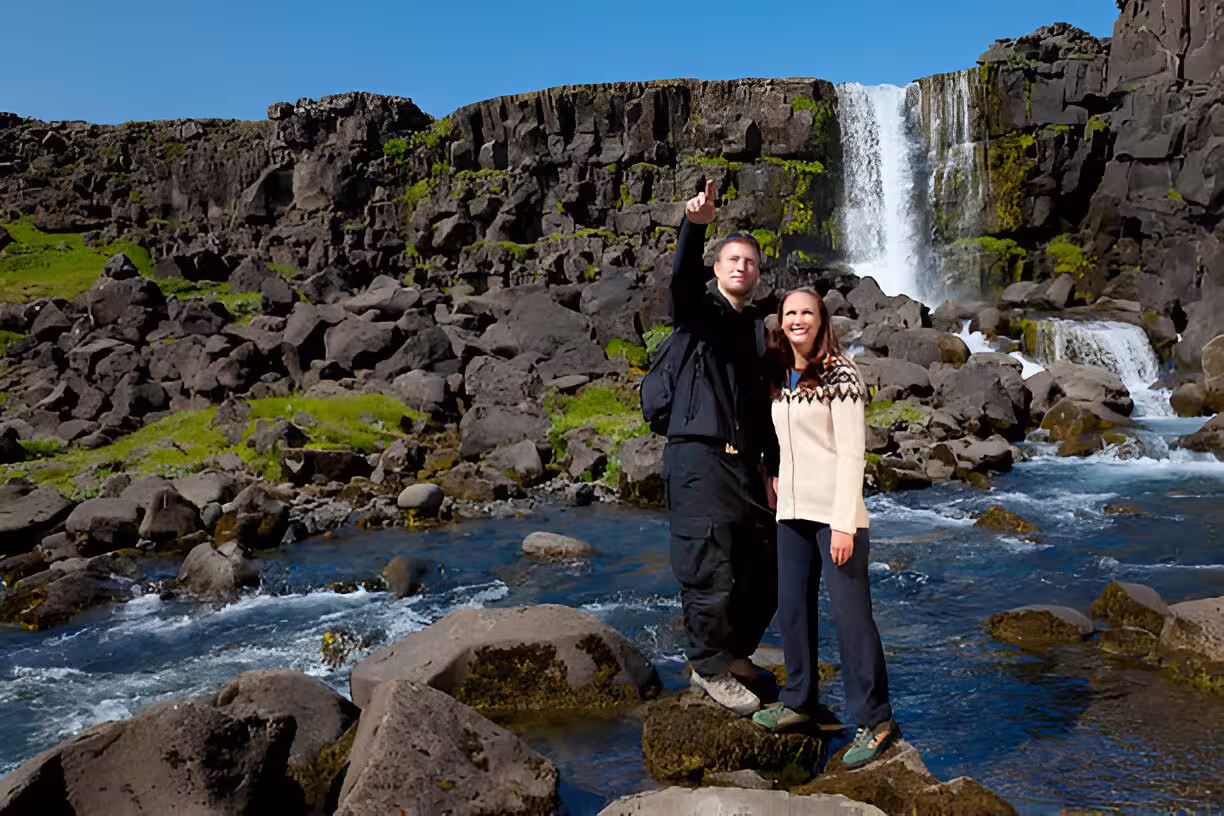 Couple standing on rocks in front of Öxará waterfall at Þingvellir on Iceland Golden Circle tour