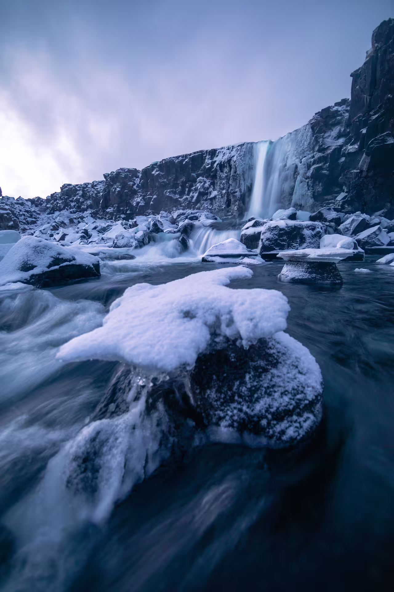 Frozen waterfall and snow-covered rocks in Iceland's Golden Circle during winter