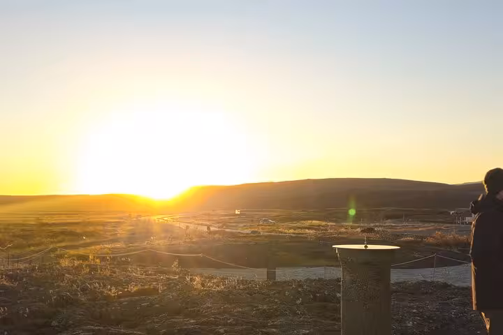 Golden sunset over Iceland's vast landscape viewed from Golden Circle overlook with visitor silhouette