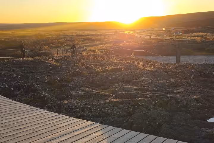 Golden sunset over Iceland's volcanic landscape with wooden boardwalk and sweeping valley views