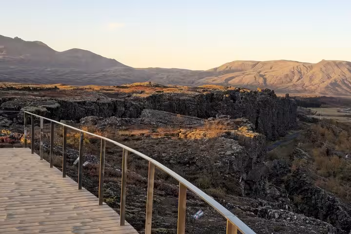 Wooden viewing platform overlooking Iceland's volcanic rock landscape and mountains at golden hour