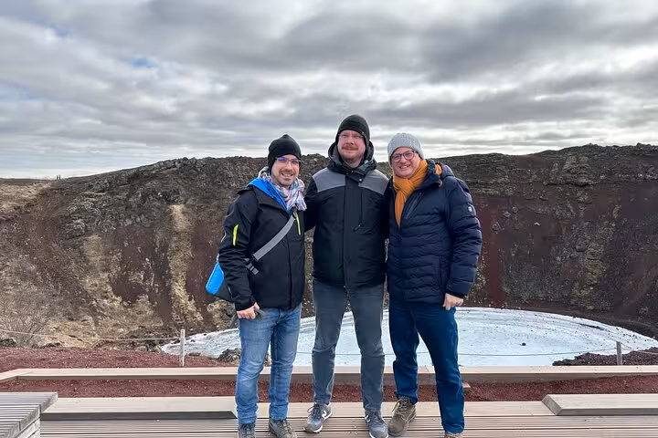 Three tourists smiling at Kerid volcanic crater lake on Iceland's Golden Circle tour