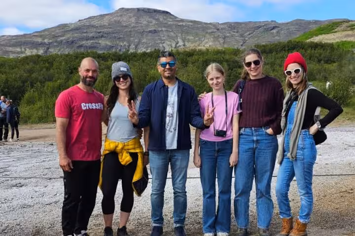 Group of six tourists posing together on Golden Circle private tour with Icelandic mountain landscape behind