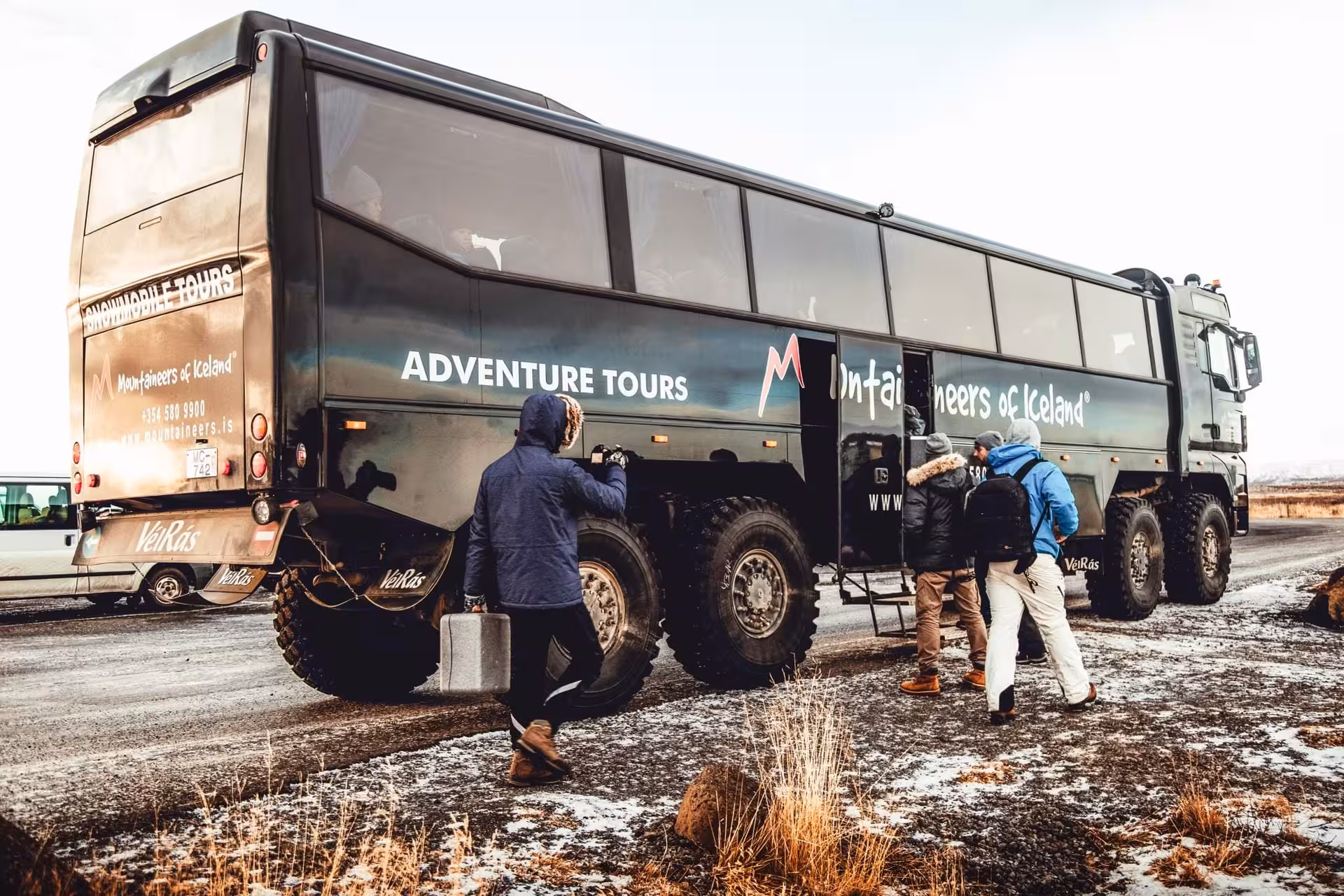 Tourists boarding a large Mountaineers of Iceland super jeep adventure tour vehicle for the Golden Circle snowmobile tour departing from Reykjavik Iceland.