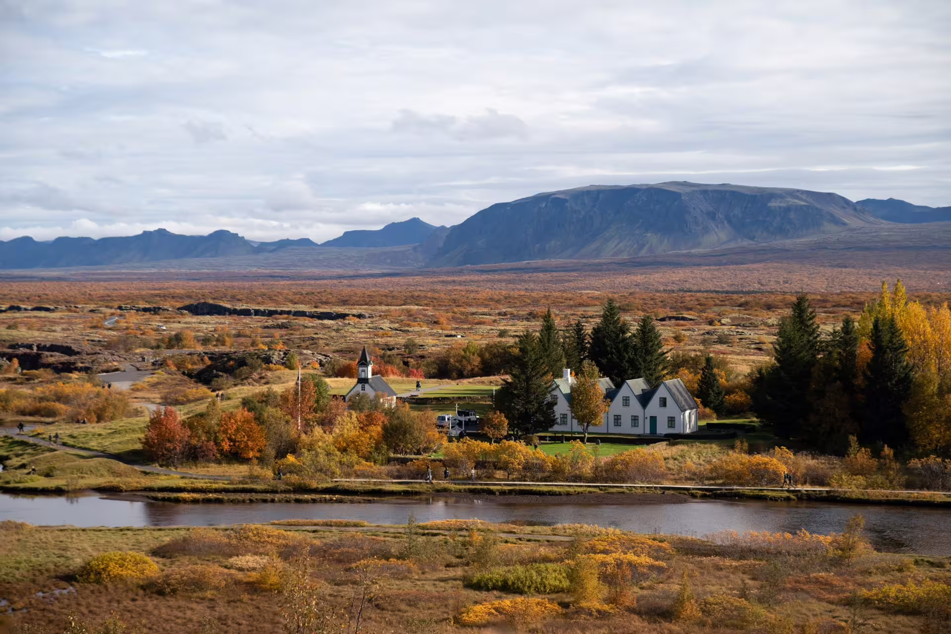 Aerial view of Þingvellir National Park in autumn with church, white farmhouse, river, and volcanic mountains