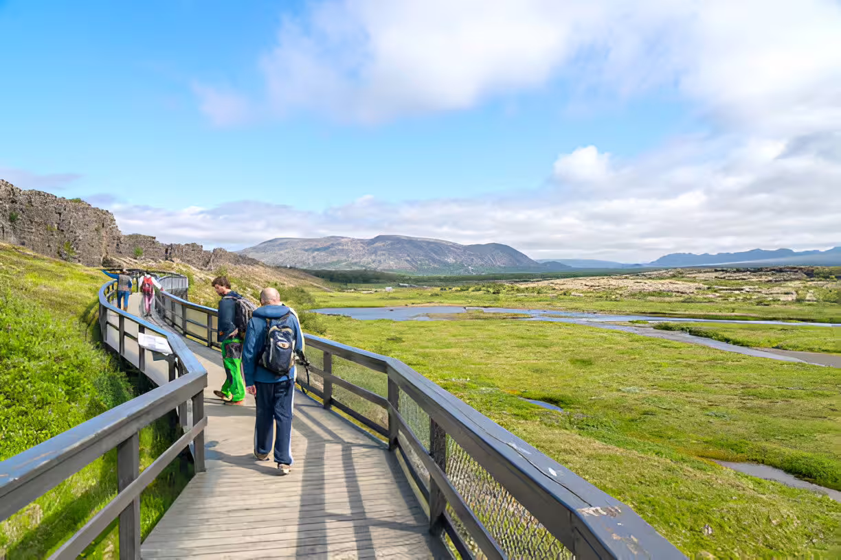 Tourists walking wooden boardwalk at Þingvellir National Park on Golden Circle tour, Iceland