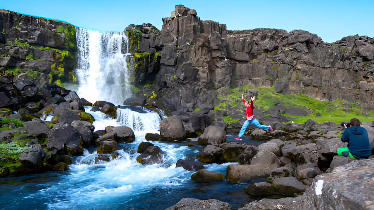 Child jumping on rocks beside Öxará River waterfall at Þingvellir National Park, Iceland Golden Circle