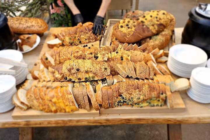 Assorted sliced artisan breads with olives and seeds displayed on wooden board at Golden Circle tour