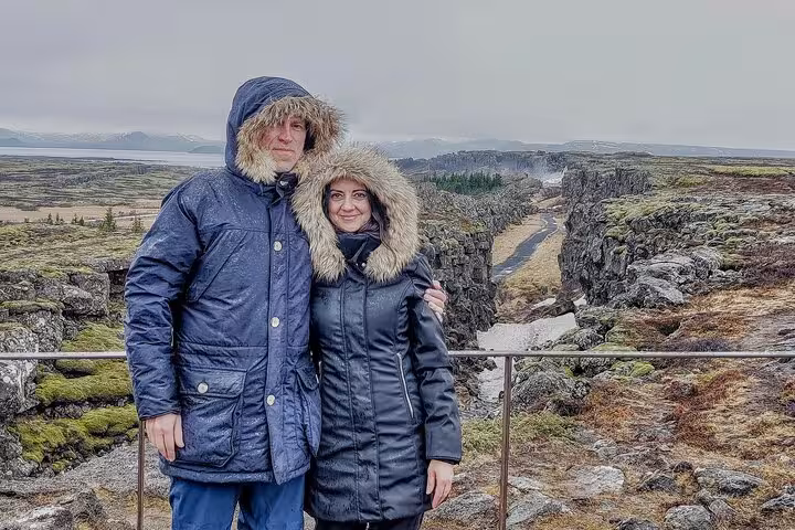 Couple in winter jackets at Þingvellir tectonic rift canyon on Golden Circle tour, Iceland