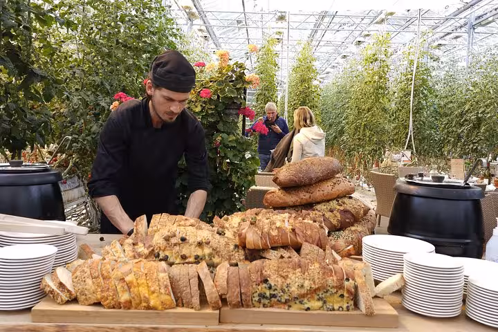 Chef arranging artisan breads on wooden board at a greenhouse buffet in Iceland