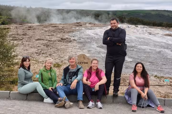 Group of six tourists posing at Geysir sign on Iceland's Golden Circle tour