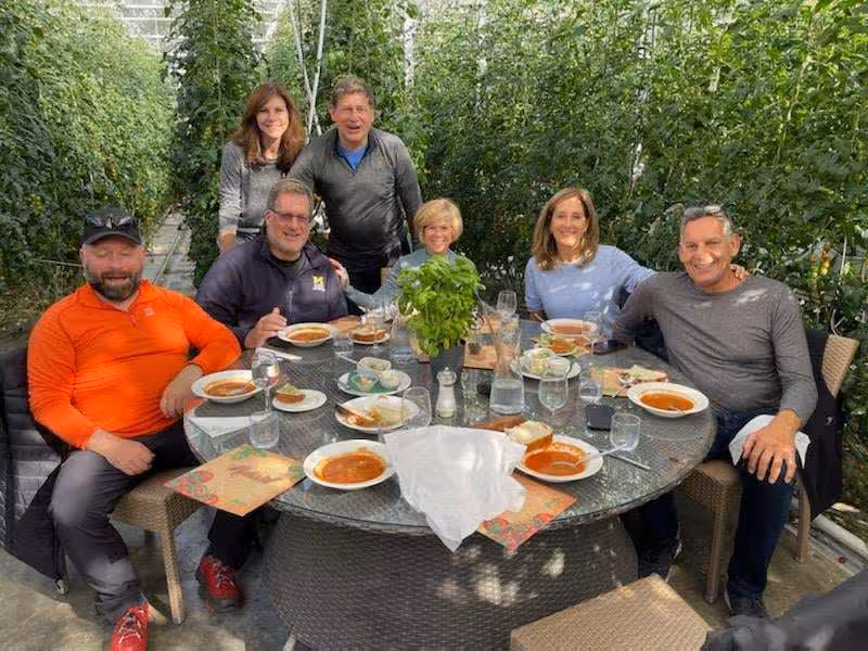 Group dining at a table inside an Icelandic greenhouse farm with tomato plants during Golden Circle tour