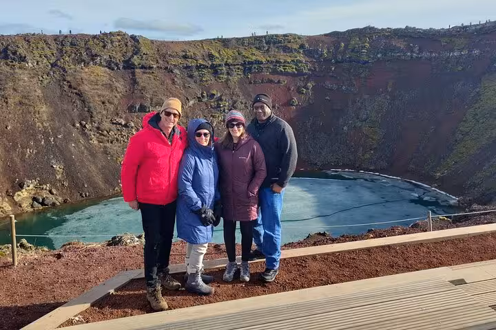 Four tourists posing at Kerid volcanic crater lake on Golden Circle tour from Reykjavik