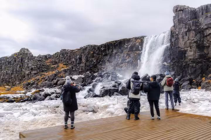 Tourists viewing Öxará waterfall on wooden viewing platform at Þingvellir, Golden Circle Iceland