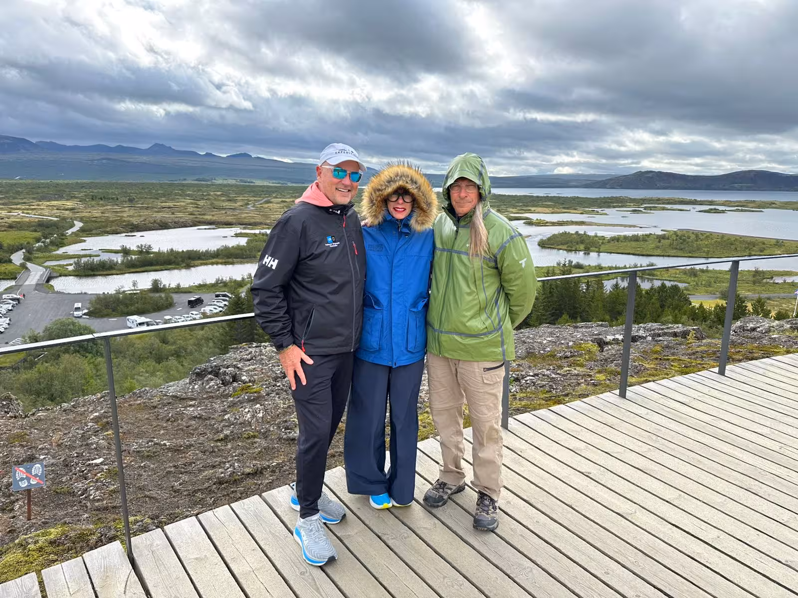 Three tourists posing at Thingvellir overlook with wetlands and lake views on Golden Circle tour
