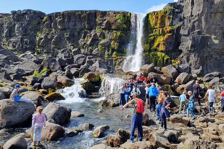 Tourists exploring rocky landscape near Öxará waterfall on Golden Circle tour in Iceland