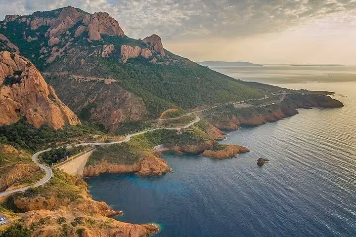 Scenic aerial view of the Golden Coast winding coastal road along rugged red cliffs and turquoise Mediterranean Sea