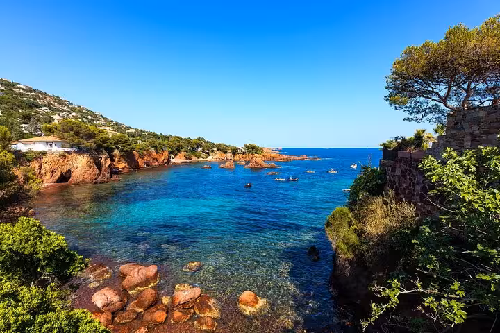 Stunning turquoise cove with red rocks and lush greenery along the Golden Coast French Riviera day trip