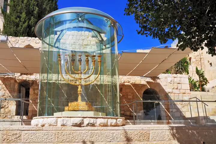 Golden menorah display in glass cylinder near Jerusalem's Western Wall plaza