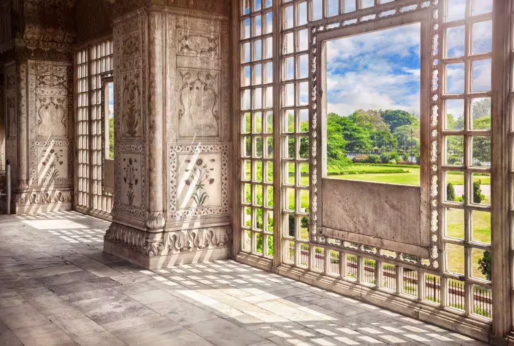 Intricately carved marble columns and open windows offering lush garden views on the Classic Golden Triangle tour.