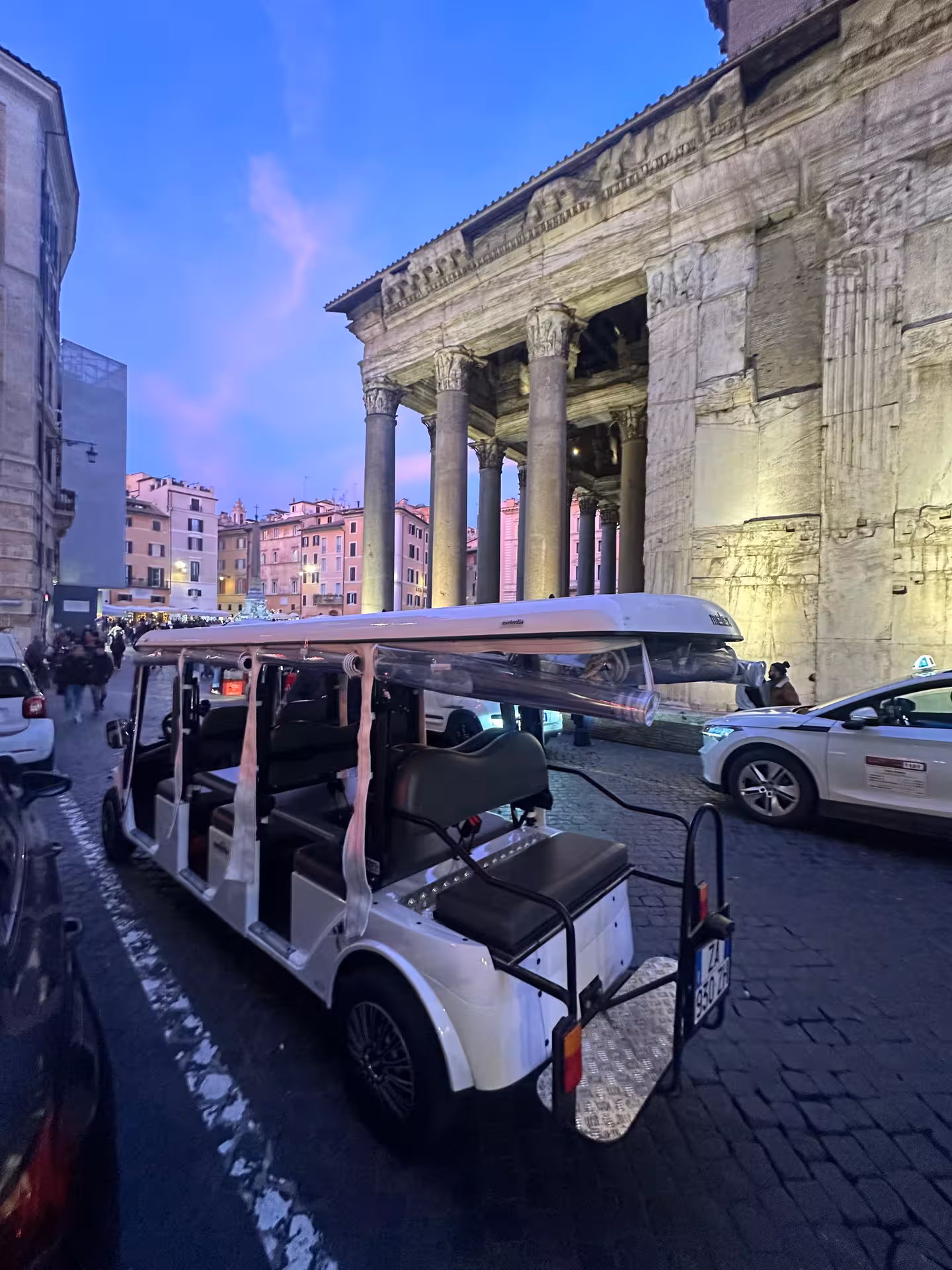 Golf cart parked near illuminated ancient Roman ruins on a Hidden Rome by Night tour.