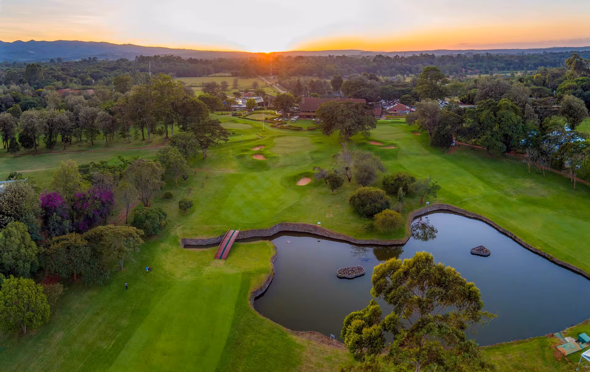 Scenic aerial view of a golf course at sunset, showcasing a tranquil setting ideal for a golf and safari group package.