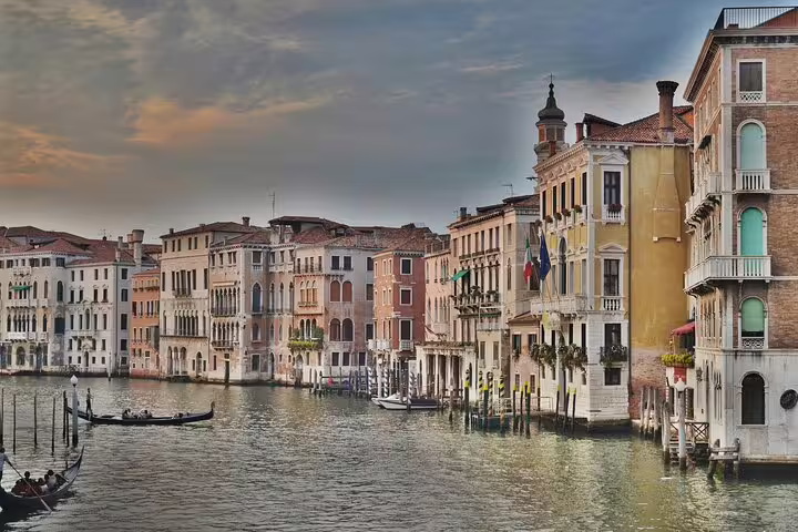 Gondolas gliding along the Grand Canal at sunset, lined with ornate palaces on a last minute Venice private tour