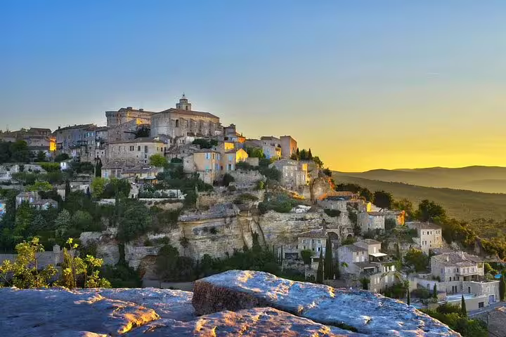 Golden sunset over the hilltop village of Gordes with stone buildings and cliffs in Luberon, Provence