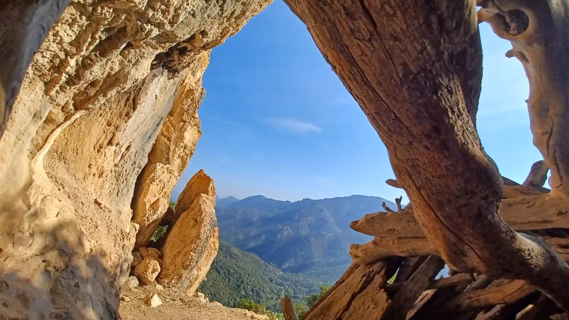Stunning view of Gorropu canyon framed by rugged cave walls and vibrant blue skies in Sardinia.