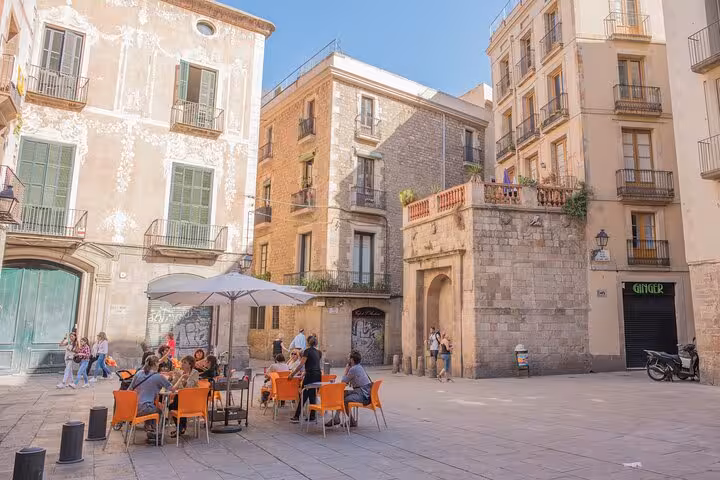 Sunny medieval plaza in Barcelona's Gothic Quarter with outdoor café seating and historic stone buildings