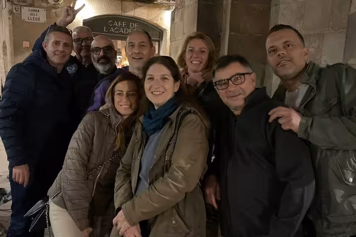 Group of tourists smiling outside Cafe de l'Acadèmia in Barcelona's Gothic Quarter at night
