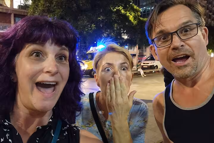 Three excited tourists reacting with surprise during a night tour in Barcelona's Gothic Quarter