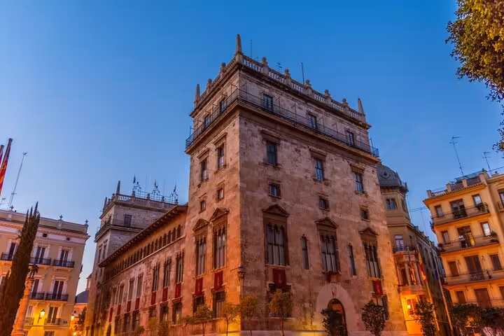 Historic Gothic stone building illuminated at dusk in Barcelona's Gothic Quarter