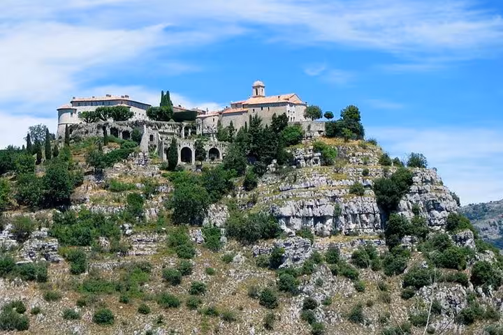 Medieval hilltop village with stone buildings and chapel overlooking rocky cliffs near Cannes countryside