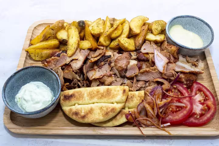 A delicious assortment of Greek cuisine featuring gyros, pita, potatoes, and dips, perfect for an Athens Ancient Greece Symposium Lunch.