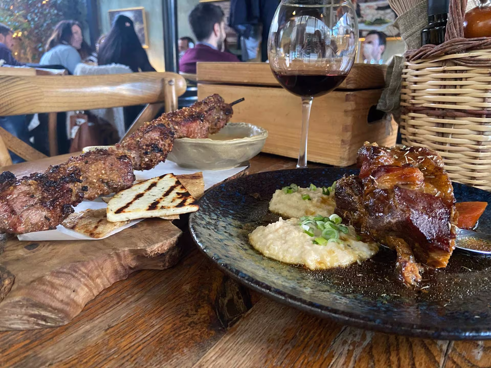 Delight in a traditional Greek symposium lunch with succulent lamb, grilled skewers, creamy hummus, and wine in vibrant Athens.