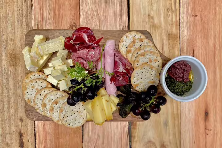 Gourmet charcuterie board with assorted cheeses, meats, crackers, and spreads, featured on a food and drink tour.